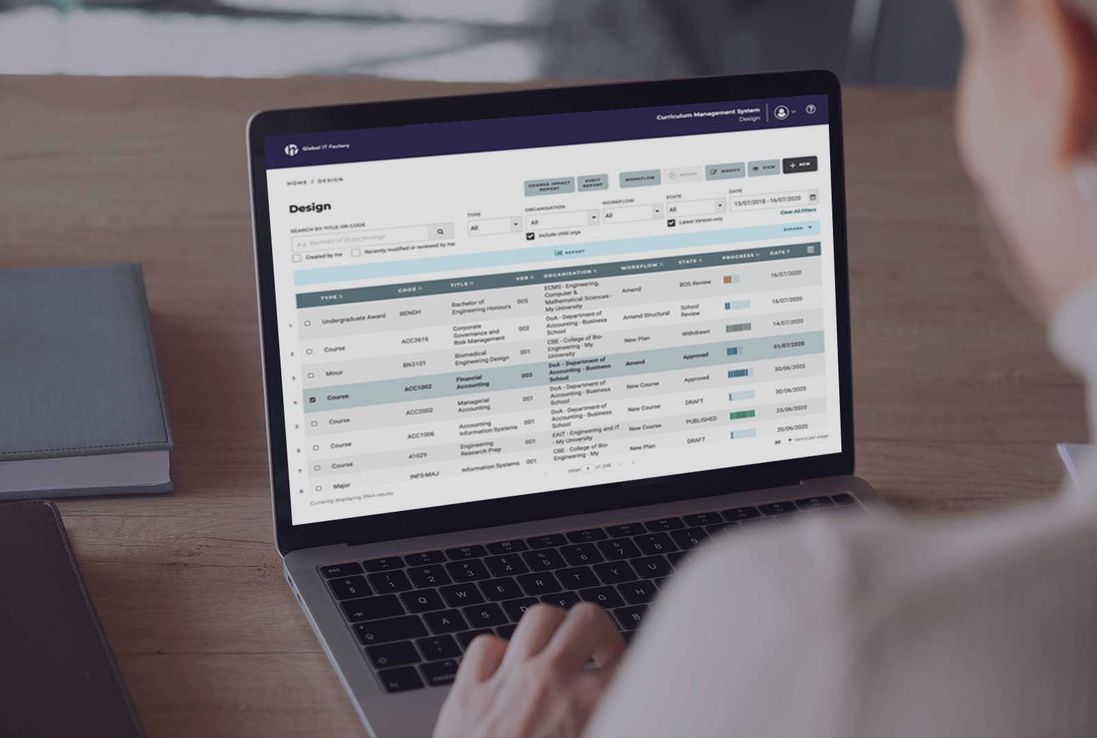 A person working on a laptop displaying a curriculum management software interface.